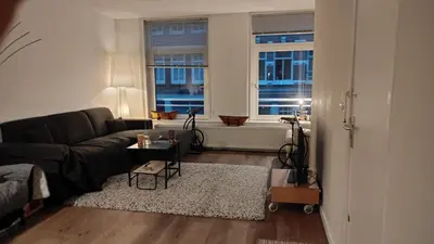a living room with a black couch and a table at Cozy Apartment in the Centre of Amsterdam in Amsterdam