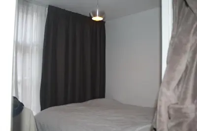 a bedroom with a bed with a black curtain and a window at Cozy Apartment in the Centre of Amsterdam in Amsterdam