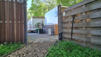 a wooden fence next to a yard with a patio at City Farmer Farmyard Stays, Sleep Easy, Stay Rural, Explore Amsterdam in Amsterdam