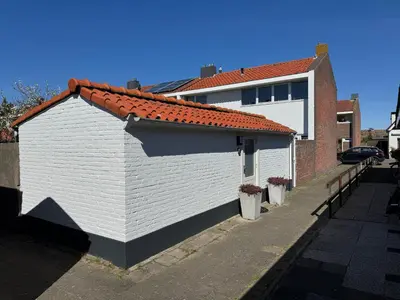a white building with a red roof on a street at Wanderlust - Vlakbij strand - Omheinde privétuin in Noordwijk aan Zee