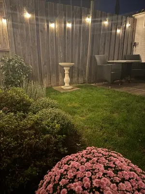 a yard with pink flowers and a table and a fence at Wanderlust - Vlakbij strand - Omheinde privétuin in Noordwijk aan Zee