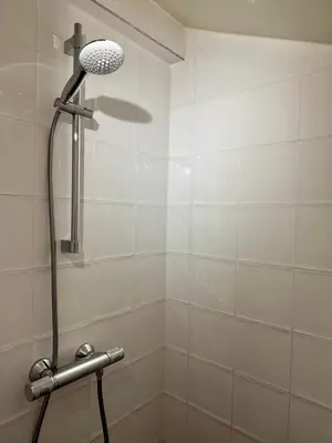 a shower with a shower head in a bathroom at Wanderlust - Vlakbij strand - Omheinde privétuin in Noordwijk aan Zee