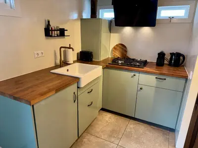 a small kitchen with a sink and a stove at Wanderlust - Vlakbij strand - Omheinde privétuin in Noordwijk aan Zee