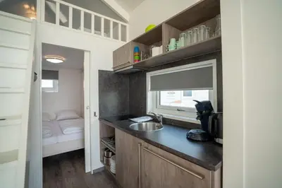 a small kitchen with a sink and a bedroom at overnachtingopstrand in Katwijk