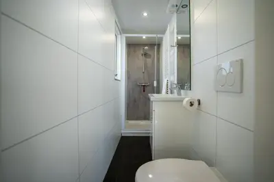 a white bathroom with a toilet and a shower at overnachtingopstrand in Katwijk