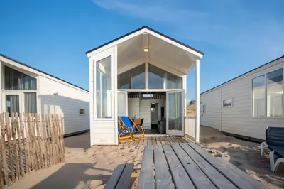 a house on the beach with a deck and chairs at overnachtingopstrand in Katwijk