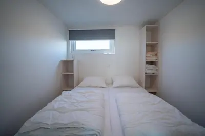 a small bedroom with a large bed with a window at overnachtingopstrand in Katwijk