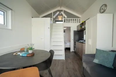 a small living room with a table and a couch at overnachtingopstrand in Katwijk