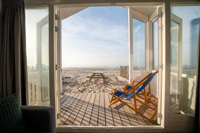 a porch with a chair and a picnic table on the beach at overnachtingopstrand in Katwijk