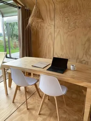 a wooden table with a laptop computer on top of it at Lakehouses luxe family holiday house 6 pers in Oud-Ade