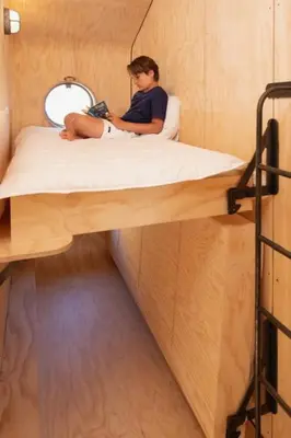 a woman sitting on a bed in a room at Lakehouses luxe family holiday house 6 pers in Oud-Ade
