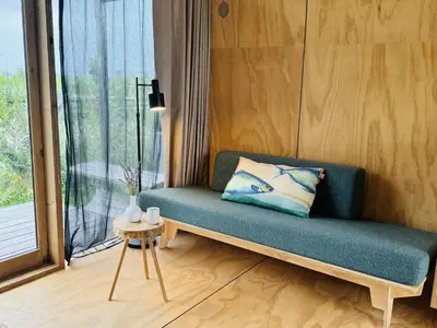 a couch sitting in a room with a window at Lakehouses luxe family holiday house 6 pers in Oud-Ade
