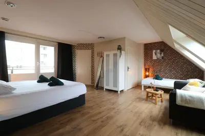 a bedroom with two beds and a brick wall at Strand appartement aan zee met 2 parkeerplekken! in Egmond aan Zee