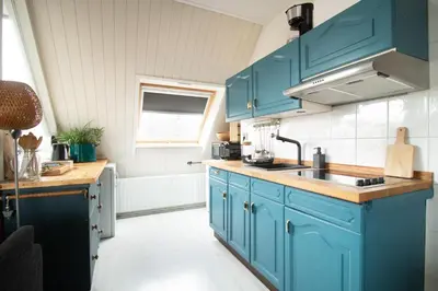 a kitchen with blue cabinets and a sink at Strand appartement aan zee met 2 parkeerplekken! in Egmond aan Zee