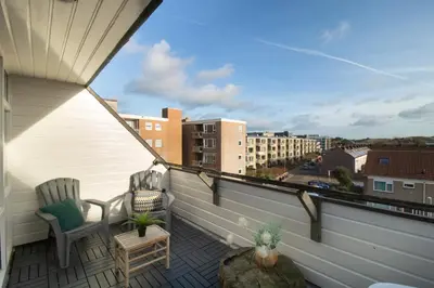 a balcony with two chairs and a view of a city at Strand appartement aan zee met 2 parkeerplekken! in Egmond aan Zee