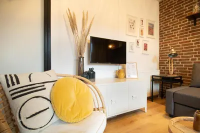 a living room with a couch and a tv at Knus appartement met parkeerplek en zeezicht! in Egmond aan Zee