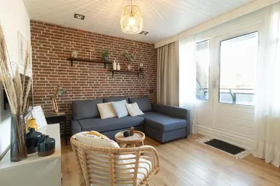 a living room with a couch and a brick wall at Knus appartement met parkeerplek en zeezicht! in Egmond aan Zee