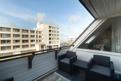 two chairs on a balcony with a view of a building at Knus appartement met parkeerplek en zeezicht! in Egmond aan Zee