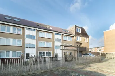 an apartment building with a fence in front of it at Knus appartement met parkeerplek en zeezicht! in Egmond aan Zee