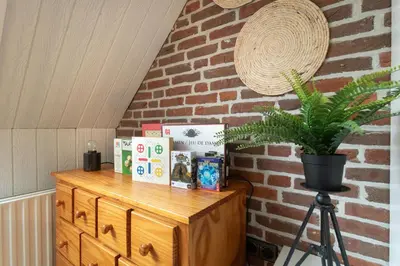 a wooden dresser with books and a plant on it at Knus appartement met parkeerplek en zeezicht! in Egmond aan Zee