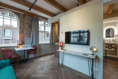 a living room with a desk and chairs and windows at Studio Urbain by Grapèlli Boutique Hotel in Alkmaar