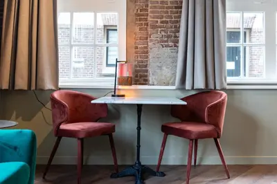 two chairs and a table in a room with windows at Studio Urbain by Grapèlli Boutique Hotel in Alkmaar