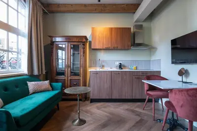 a living room with a green couch and a kitchen at Studio Urbain by Grapèlli Boutique Hotel in Alkmaar