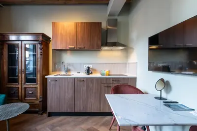 a kitchen with wooden cabinets and a white table at Studio Urbain by Grapèlli Boutique Hotel in Alkmaar