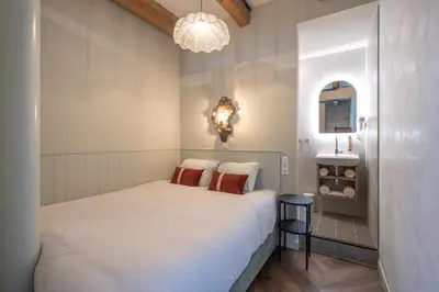 a small bedroom with a white bed and a chandelier at Studio Urbain by Grapèlli Boutique Hotel in Alkmaar