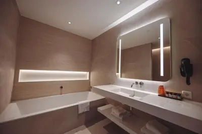a bathroom with a tub and a sink and a mirror at Van der Valk Hotel Houten Utrecht in Houten