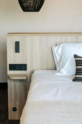 a bedroom with a white bed with a wooden headboard at Van der Valk Hotel Houten Utrecht in Houten