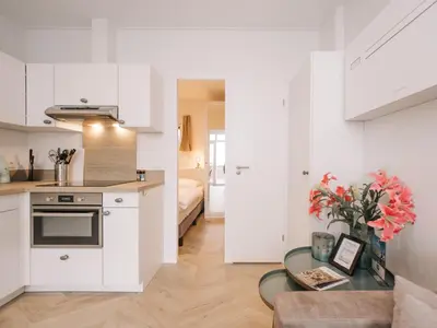 a kitchen and living room with white cabinets and a table at Suite 55, near the beach in Zandvoort