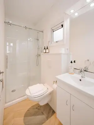 a white bathroom with a toilet and a shower at Suite 55, near the beach in Zandvoort