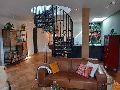 a living room with a couch and a spiral staircase at Luxurious house close to the center of Amsterdam in Oostzaan