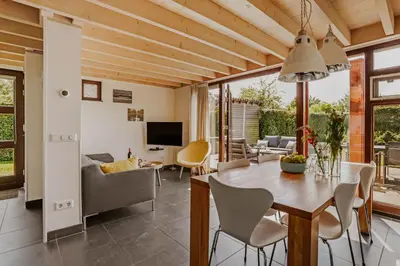 a dining room and living room with a table and chairs at Dutchen Vakantiepark Buiten Bergen in Schoorl