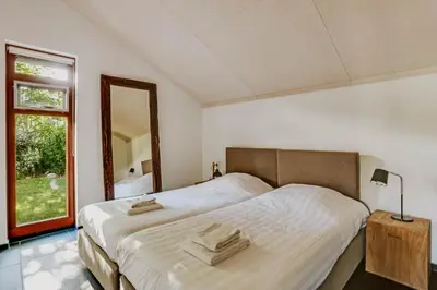 a bedroom with a large bed and a mirror at Dutchen Vakantiepark Buiten Bergen in Schoorl