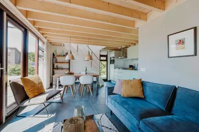 a living room with a blue couch and a table at Dutchen Vakantiepark Buiten Bergen in Schoorl