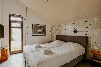 a bedroom with a large bed and a window at Dutchen Vakantiepark Buiten Bergen in Schoorl