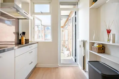 a kitchen with white cabinets and a large window at Stunning artist zen guest suite at heart of Amsterdam in Amsterdam