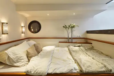 a bedroom with a large bed with white sheets at Your Houseboat Amsterdam in Amsterdam