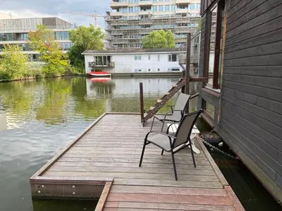 a wooden dock with two chairs sitting on top of the water at T kan Verkeren - Houseboat in Amsterdam