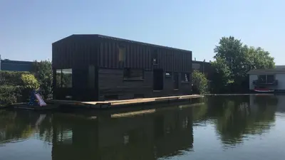 a house on a dock on a body of water at T kan Verkeren - Houseboat in Amsterdam