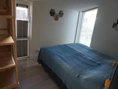 a bedroom with a bed with a blue bedspread and two windows at Beautiful Villa close to beaches in Sint Maarten
