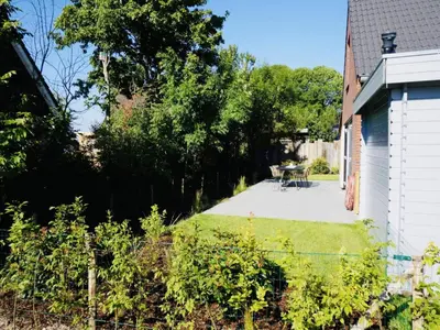 a backyard with a patio and a table and some bushes at Beautiful Villa close to beaches in Sint Maarten