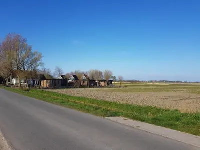 an empty road next to a field and houses at Pretty holiday home in Burgerburg in Burgerbrug