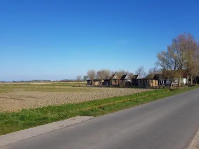 an empty road next to a field with houses at Pretty holiday home in Burgerburg in Burgerbrug