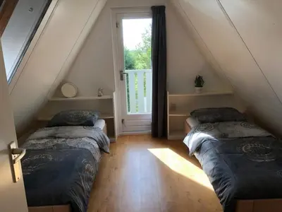 two beds in a attic room with a window at Pretty holiday home in Burgerburg in Burgerbrug