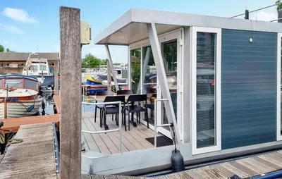 a small boat with a deck with a table at Havenlodge Amsterdam 1 in Amsterdam