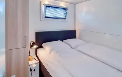 a bed in a small room with a window at Havenlodge Amsterdam 1 in Amsterdam