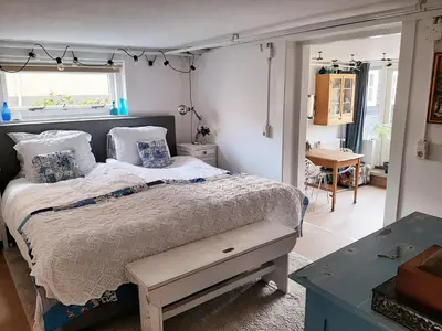 a bedroom with a bed and a window and a table at Gezellig souterrain in bollestreek met prive ingang in Hillegom